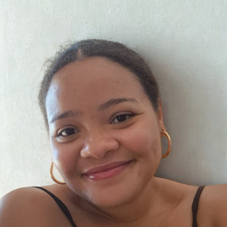 A woman smiling softly at the camera against a light background.